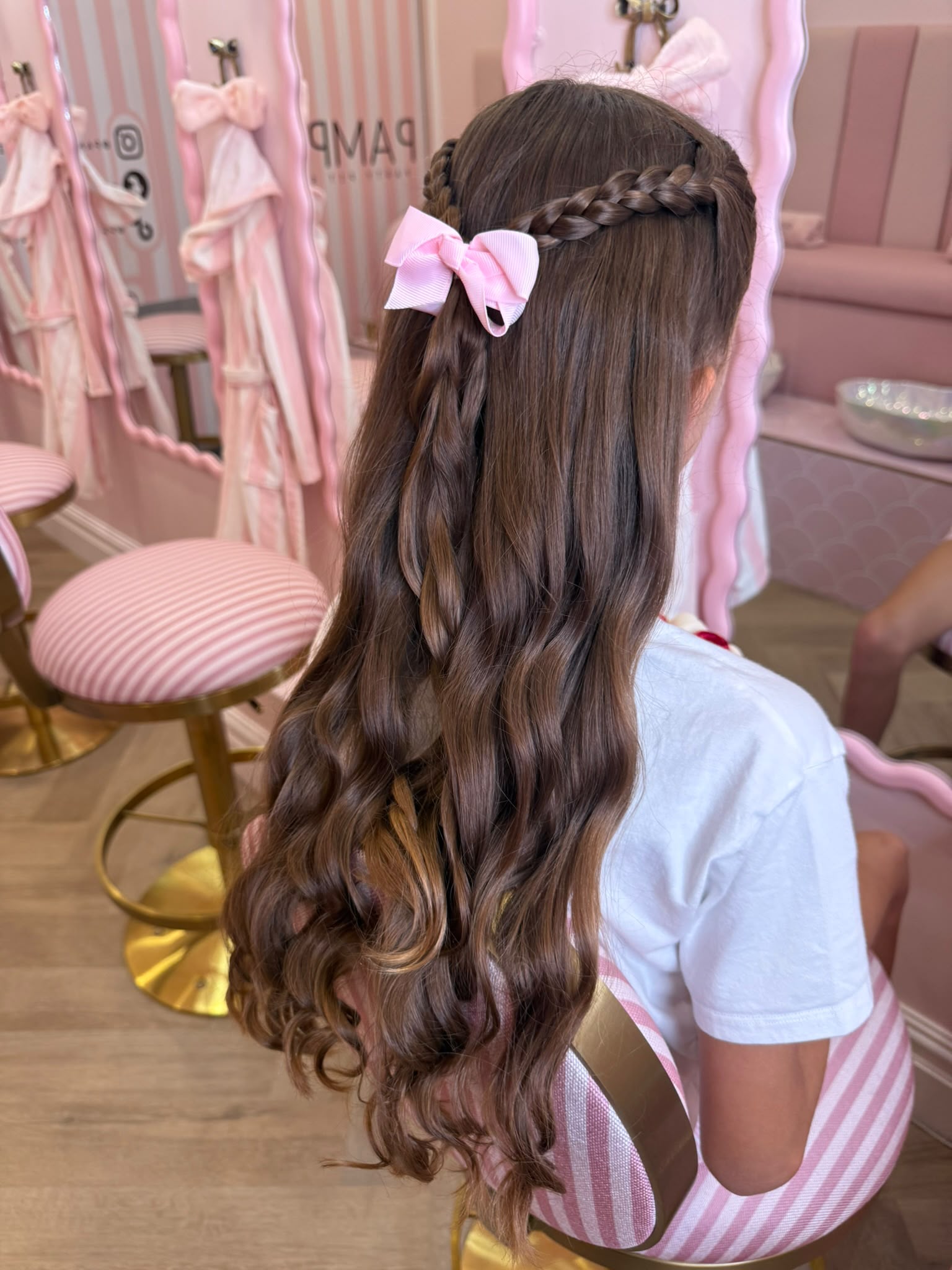 Long curled hair with a braid and pink bow